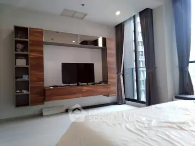 Modern bedroom with sleek TV unit and large windows offering city views.