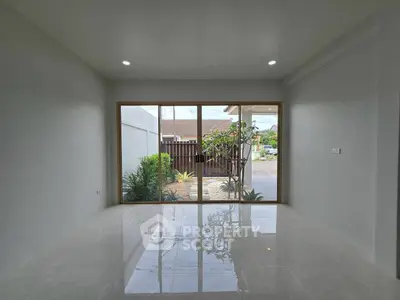 Spacious modern living room with large glass doors opening to a serene garden view.