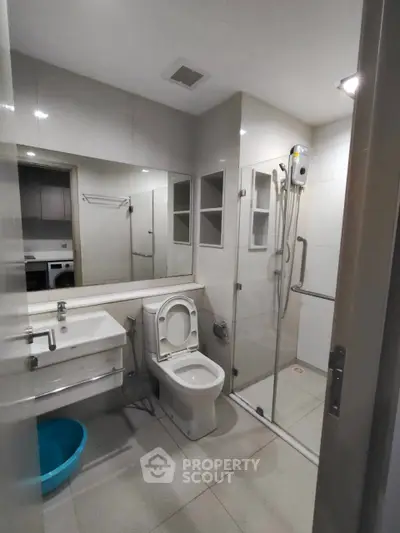 Modern bathroom with glass shower, sleek fixtures, and ample storage space.