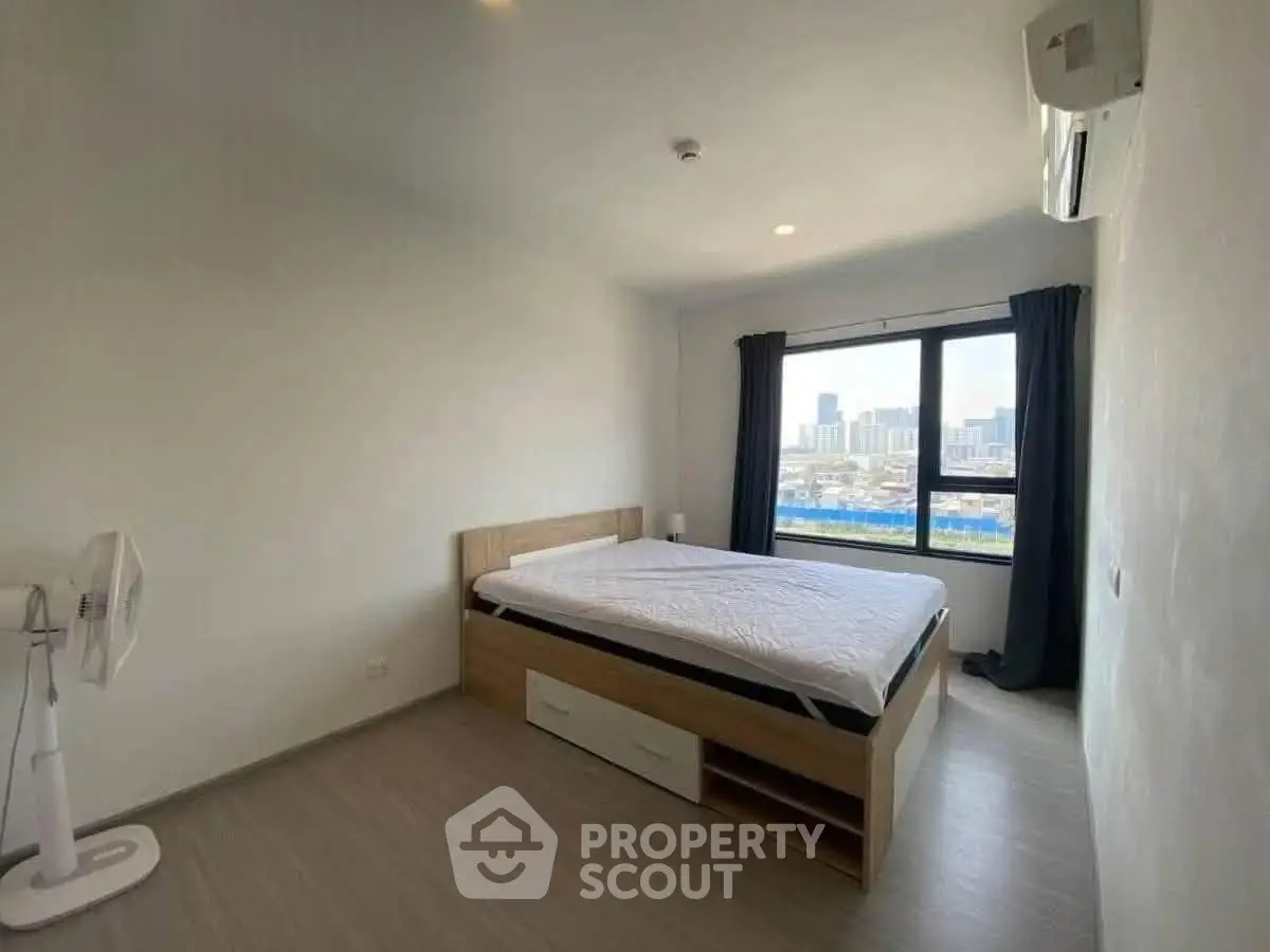 Spacious bedroom with city view, featuring modern bed and air conditioning.