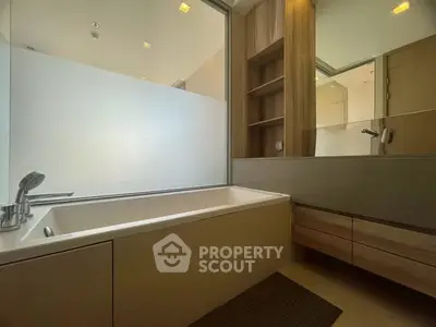 Modern bathroom with sleek bathtub and wooden cabinetry, offering a serene and minimalist design.