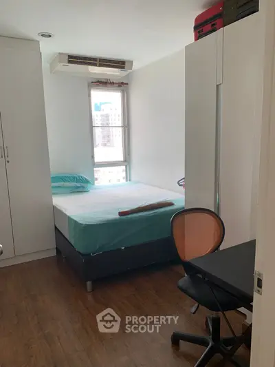 Cozy bedroom with modern furnishings and city view window, ideal for urban living.