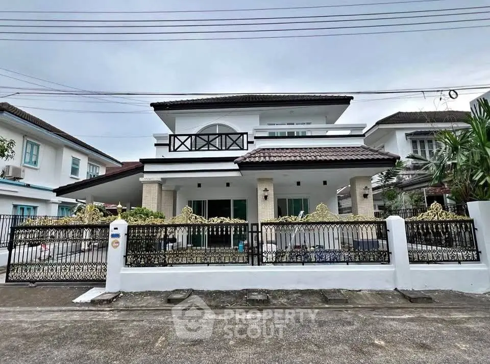 Charming two-story house with elegant balcony and ornate fence in a serene neighborhood.
