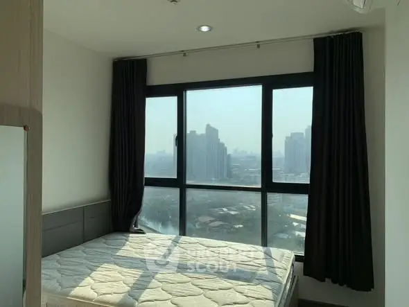 Modern bedroom with large window offering city view and natural light.