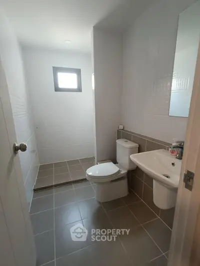 Modern bathroom with sleek fixtures and tiled walls, featuring a walk-in shower and natural light.