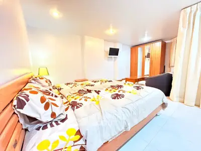 Spacious bedroom with modern decor and ample natural light, featuring a cozy bed and stylish furnishings.