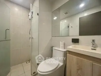 Modern bathroom with glass shower and sleek fixtures in contemporary apartment.
