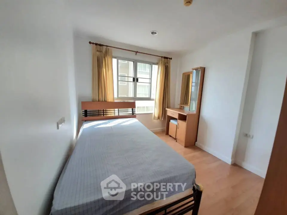 Bright bedroom with large window and wooden furniture, perfect for cozy living.
