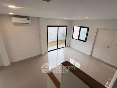 Spacious modern living room with large windows and sleek flooring, perfect for natural light and comfort.