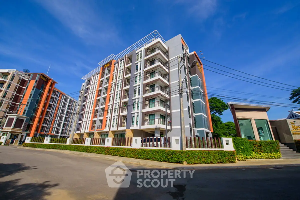 Modern multi-story apartment building with vibrant facade and lush landscaping