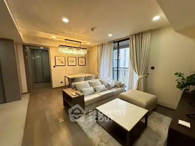 Luxurious living room with elegant chandelier and cozy seating area, featuring a small balcony view.