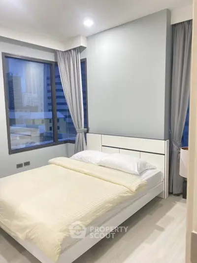 Modern bedroom with large windows and city view in a high-rise apartment.