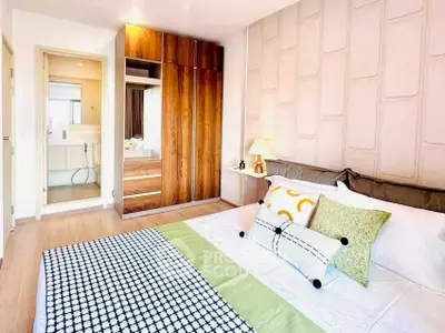 Modern bedroom with stylish decor and ensuite bathroom, featuring a wooden wardrobe and cozy bedding.