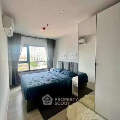 Modern bedroom with large window and stylish decor in urban apartment.