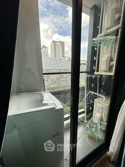Modern apartment balcony with laundry area and city view, featuring washing machine and drying rack.