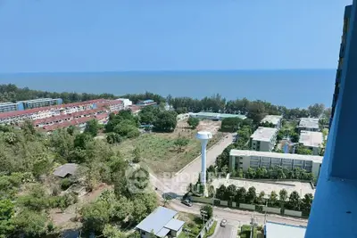 Stunning ocean view from high-rise building overlooking lush greenery and residential area.
