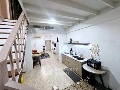 Charming open-layout kitchen with cozy living area and stylish staircase