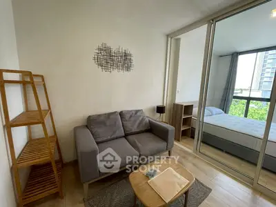 Modern apartment with cozy living room and bedroom separated by glass doors, featuring stylish decor.