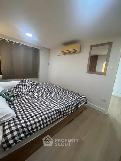 Cozy bedroom with checkered bedding and wall-mounted air conditioner