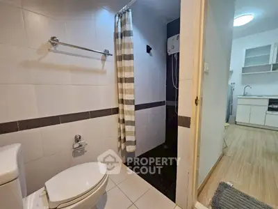 Modern bathroom with shower and adjacent kitchen area in a contemporary apartment.