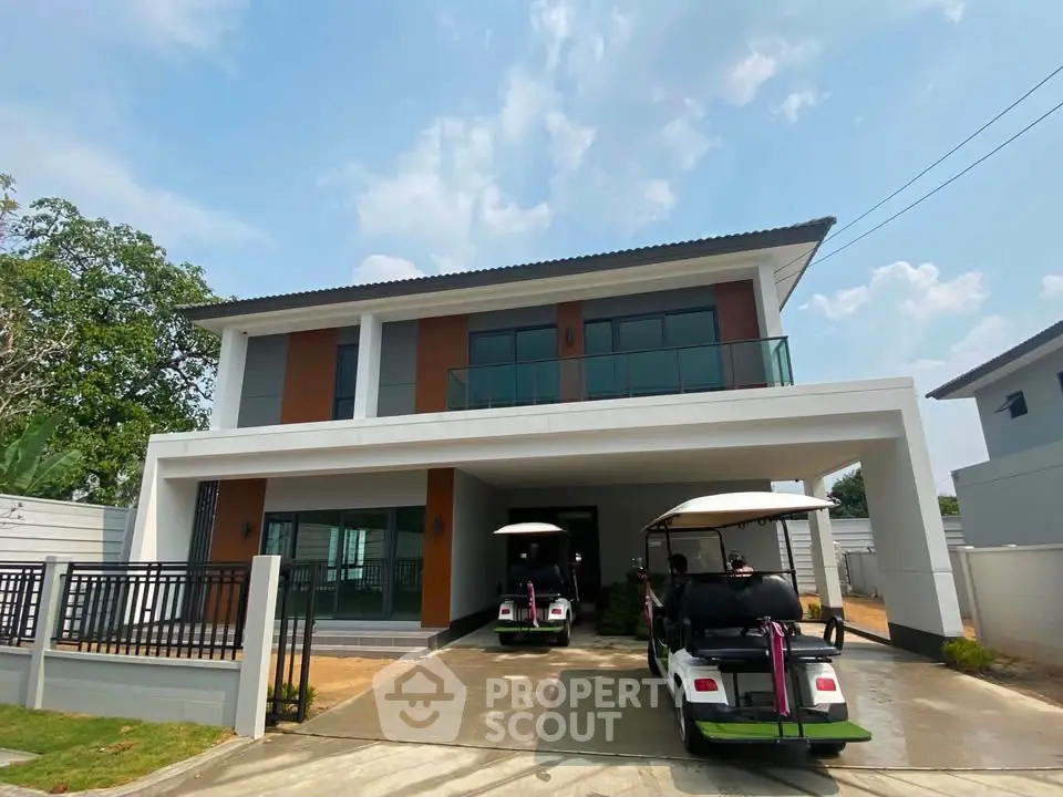 Modern two-story house with spacious driveway and golf carts, featuring sleek design and large windows.