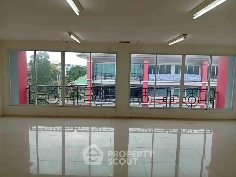 Spacious empty room with large windows offering a view of neighboring buildings, ideal for customization.