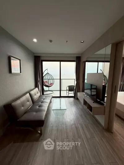 Modern living room with sea view, stylish sofa, and hanging chair on balcony.