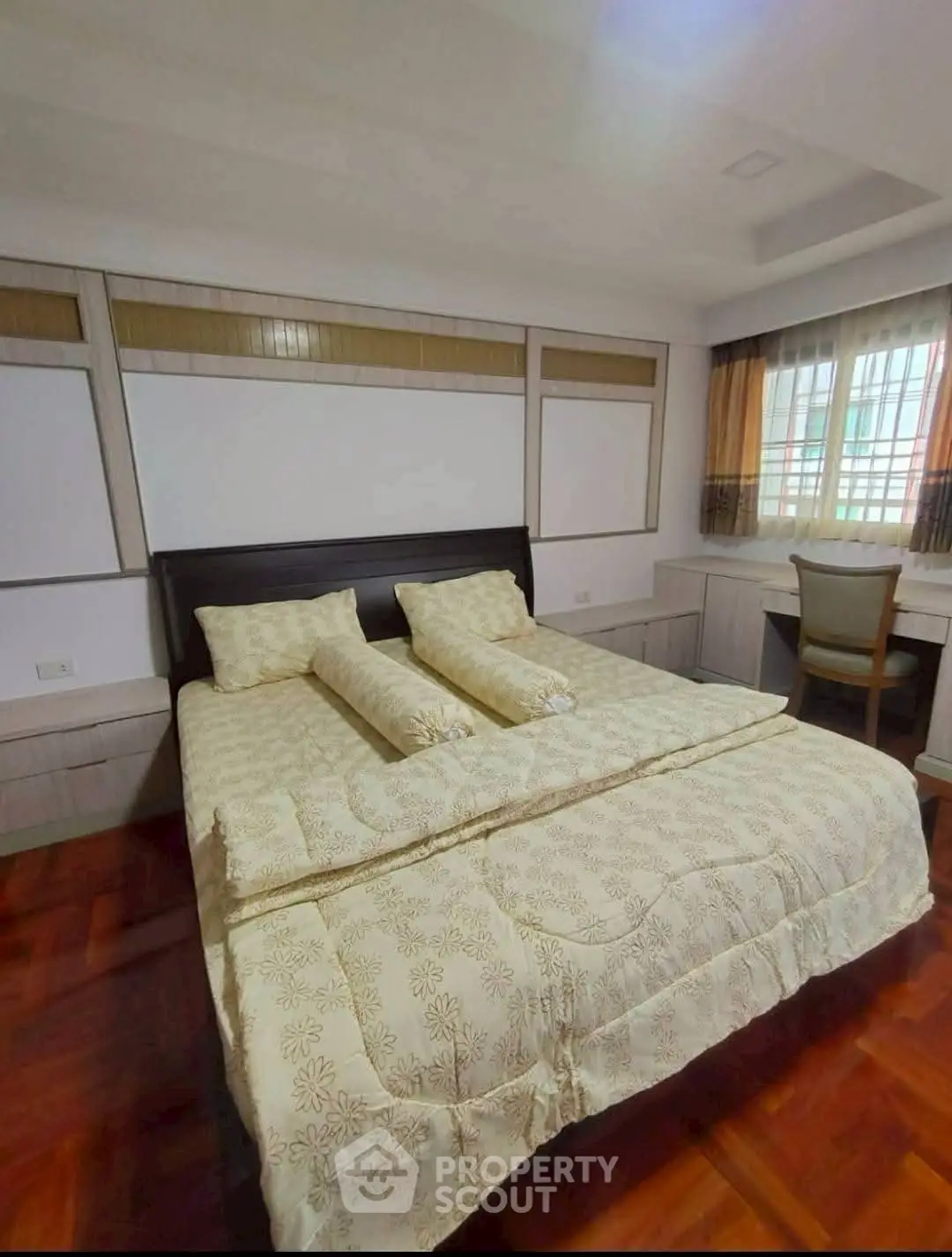 Spacious bedroom with elegant decor and wooden flooring, featuring a cozy bed and a study area.
