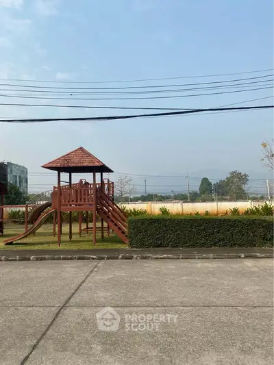 Charming outdoor playground area in a residential community with lush greenery and clear skies.