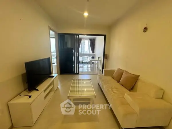 Modern living room with cozy sofa and TV, leading to a bright dining area with city view.