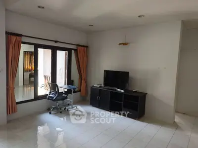 Spacious living room with modern TV stand and desk, ideal for work and relaxation.