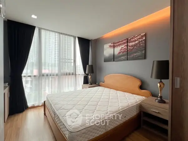 Modern bedroom with large window and stylish decor in urban apartment.