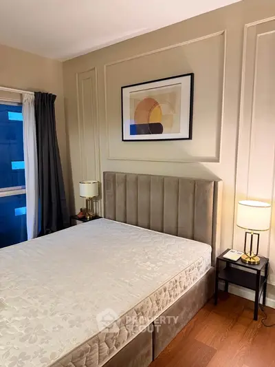 Elegant bedroom with modern decor, featuring a plush bed, stylish lamps, and framed artwork, perfect for relaxation.