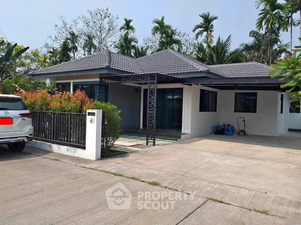 Charming single-story house with spacious driveway and lush greenery.
