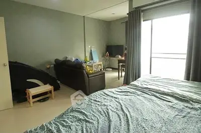 Spacious bedroom with large window and cozy seating area, perfect for relaxation.