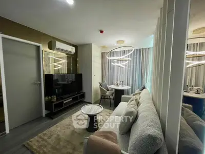 Modern living room with stylish decor and cozy seating area, featuring a large TV and elegant lighting.