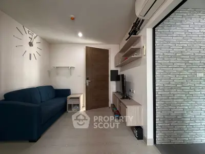 Modern living room with blue sofa, wall-mounted TV, and stylish decor.