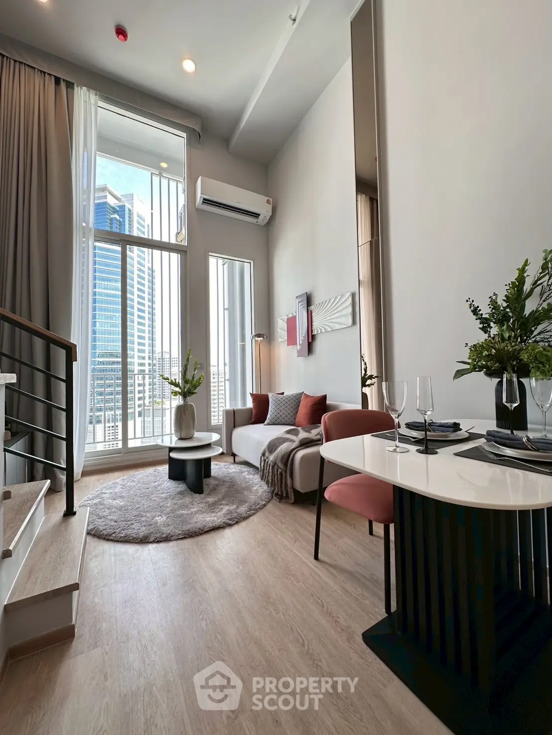 Modern living room with high ceilings and city view, featuring stylish decor and natural light.