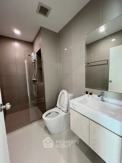 Modern bathroom with sleek design, featuring a glass shower and contemporary fixtures.