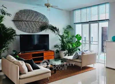 Modern living room with stylish decor, large TV, and natural light from floor-to-ceiling windows.