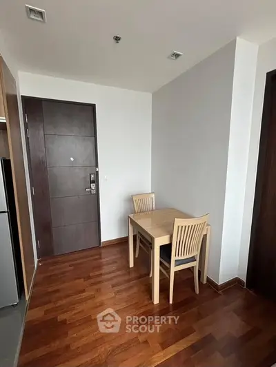 Cozy dining nook with wooden table and chairs, adjacent to modern apartment entrance.