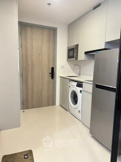 Modern compact kitchen with appliances including fridge, washing machine, and microwave.