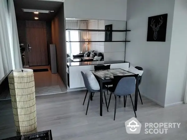 Chic modern apartment with open layout featuring a sleek dining area, stylish living room, and a well-equipped kitchen with ample lighting.