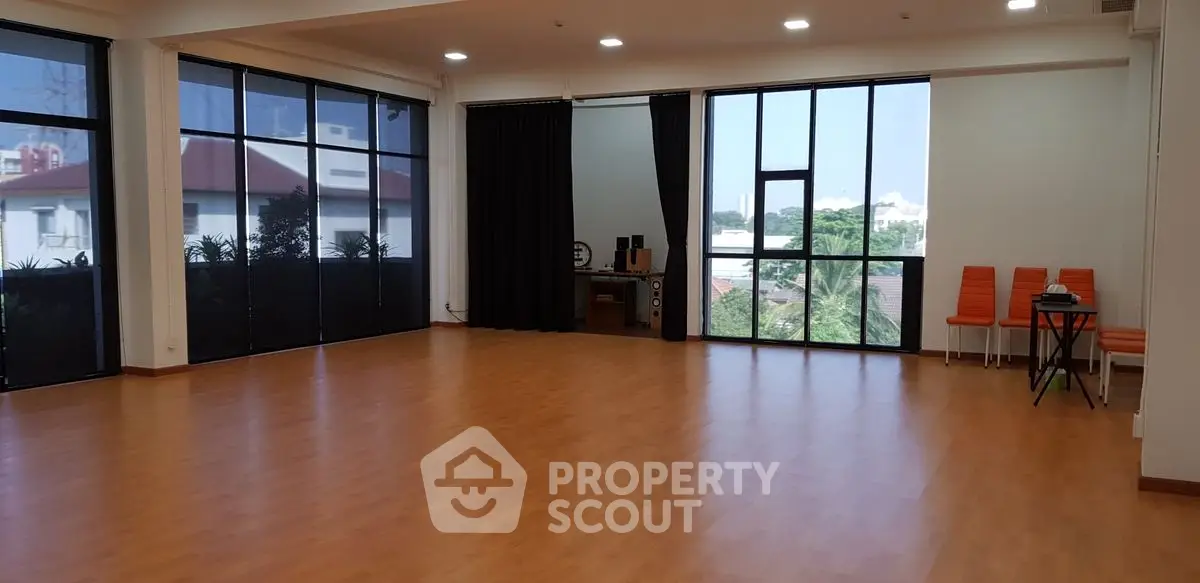 Spacious room with large windows and wooden flooring, ideal for versatile use.
