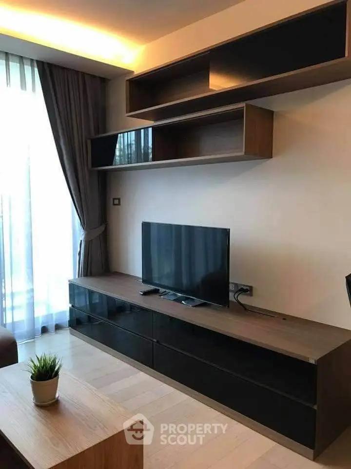 Modern living room with sleek TV stand and stylish shelving, featuring elegant curtains and natural light.