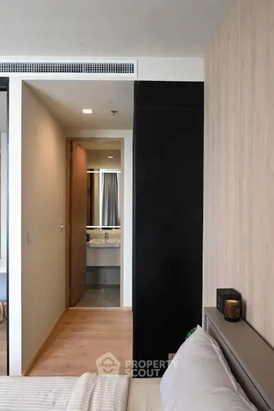 Modern bedroom with wooden accents and view into sleek bathroom
