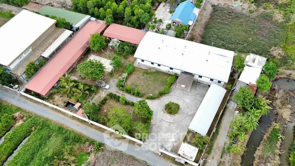 Aerial view of a spacious property with multiple buildings and lush greenery, ideal for development or investment.