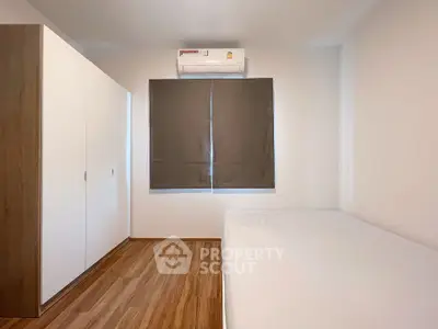 Minimalist bedroom with wooden flooring and air conditioning