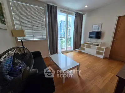 Modern living room with wooden flooring, stylish furniture, and city view from balcony.