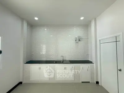 Modern minimalist kitchen with sleek white cabinetry and tiled backsplash.